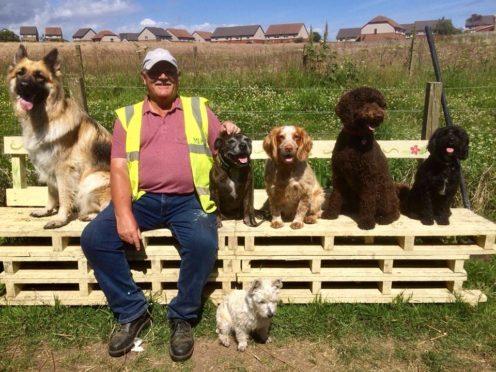 Mike Duncan (second from left) enjoys one of his hand-crafted benches on the Cove Woodland Walk.