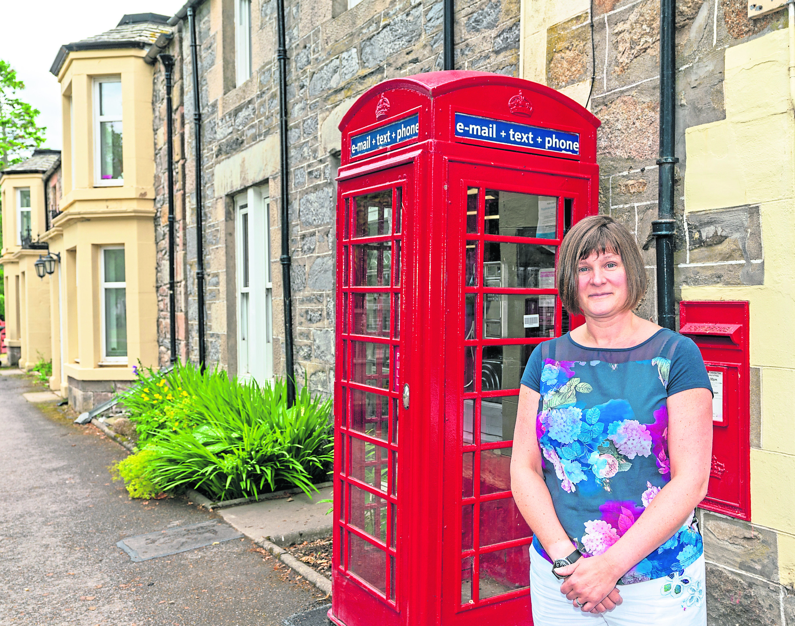 Caroline Breen in the Square at Tomintoul Village, Moray, Scotland. The telephone kiosk was to be removed by BT and is situated outside the village Post office.