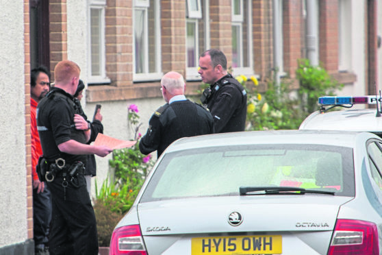 Local mission superintendent Colin Mackay, (centre), chats with police officers outside the old mission building where the crew were accommodated.