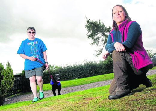 Dog breeder and trainer Lynda Hall (in red) is donating dogs to families with autistic children to help them through life. Also in the photo is Angela Drummond (blue), her son has autism.