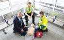 Karen Burns (right) demonstrates how to use a defibrillator to David Lister and Matthew Marshall.