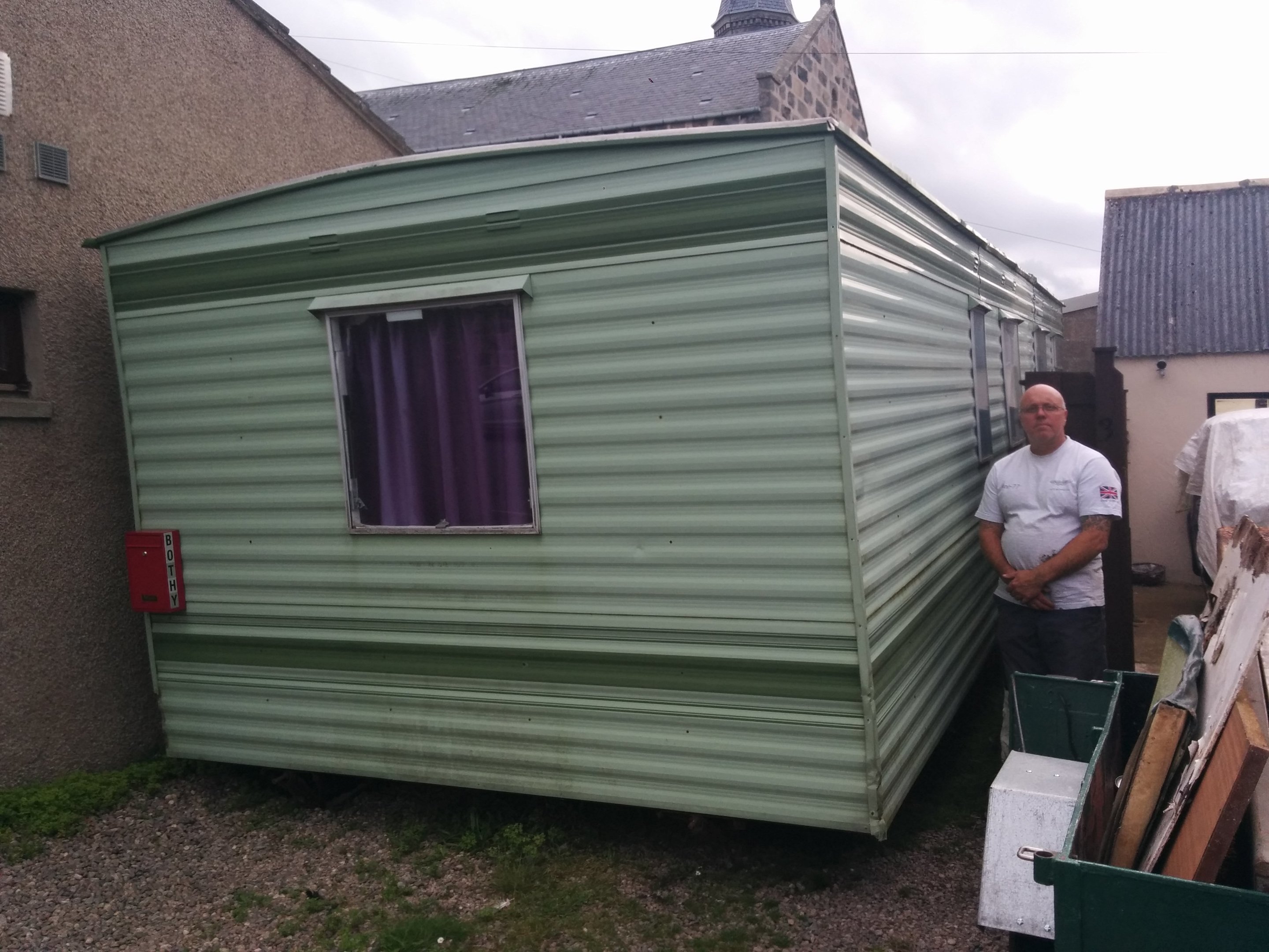 Mr Knowles stands next to the caravan between his home and the restaurant