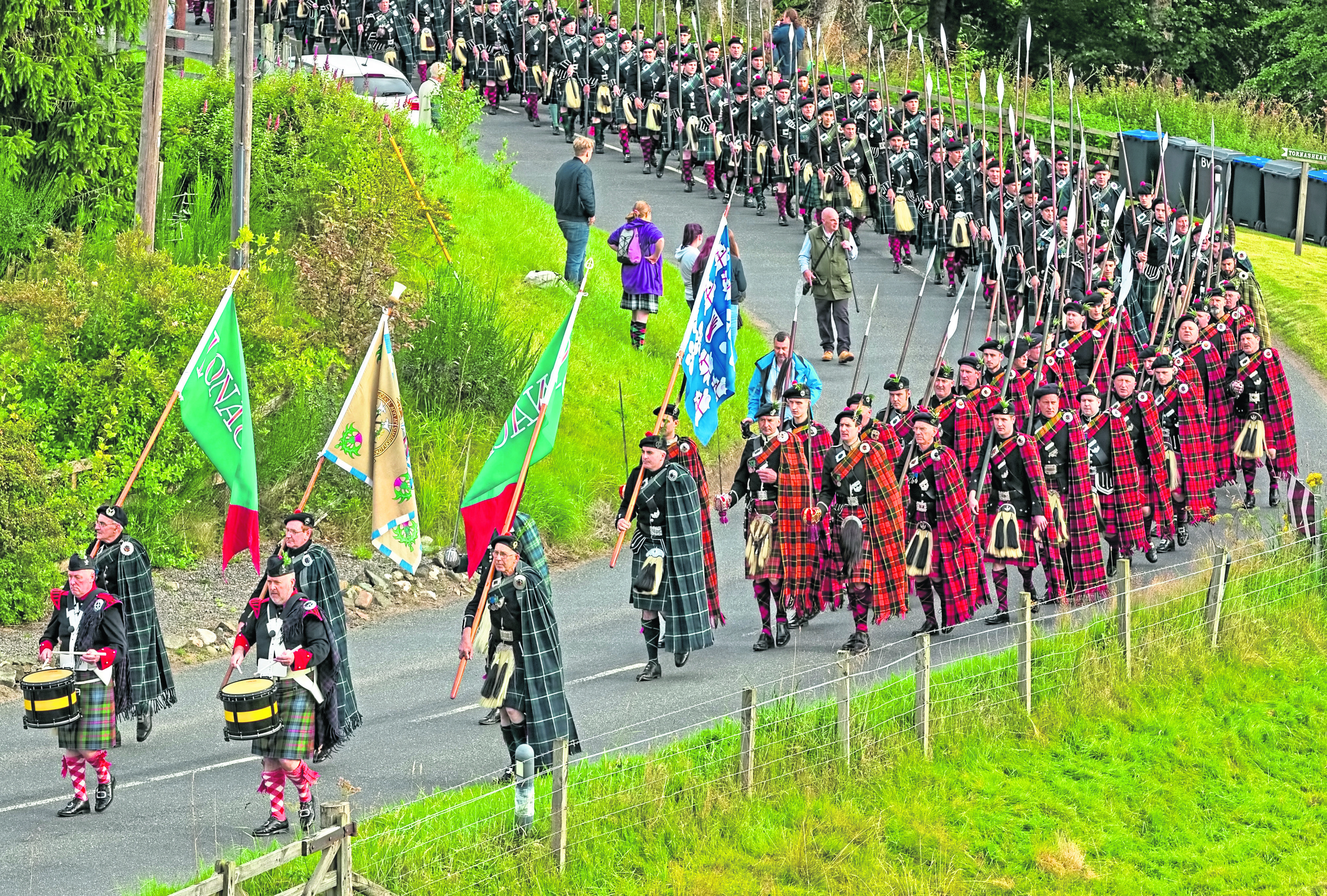 Clansmen march through the glen from Bellabeg, on their way to the Lonach Highland Gathering.