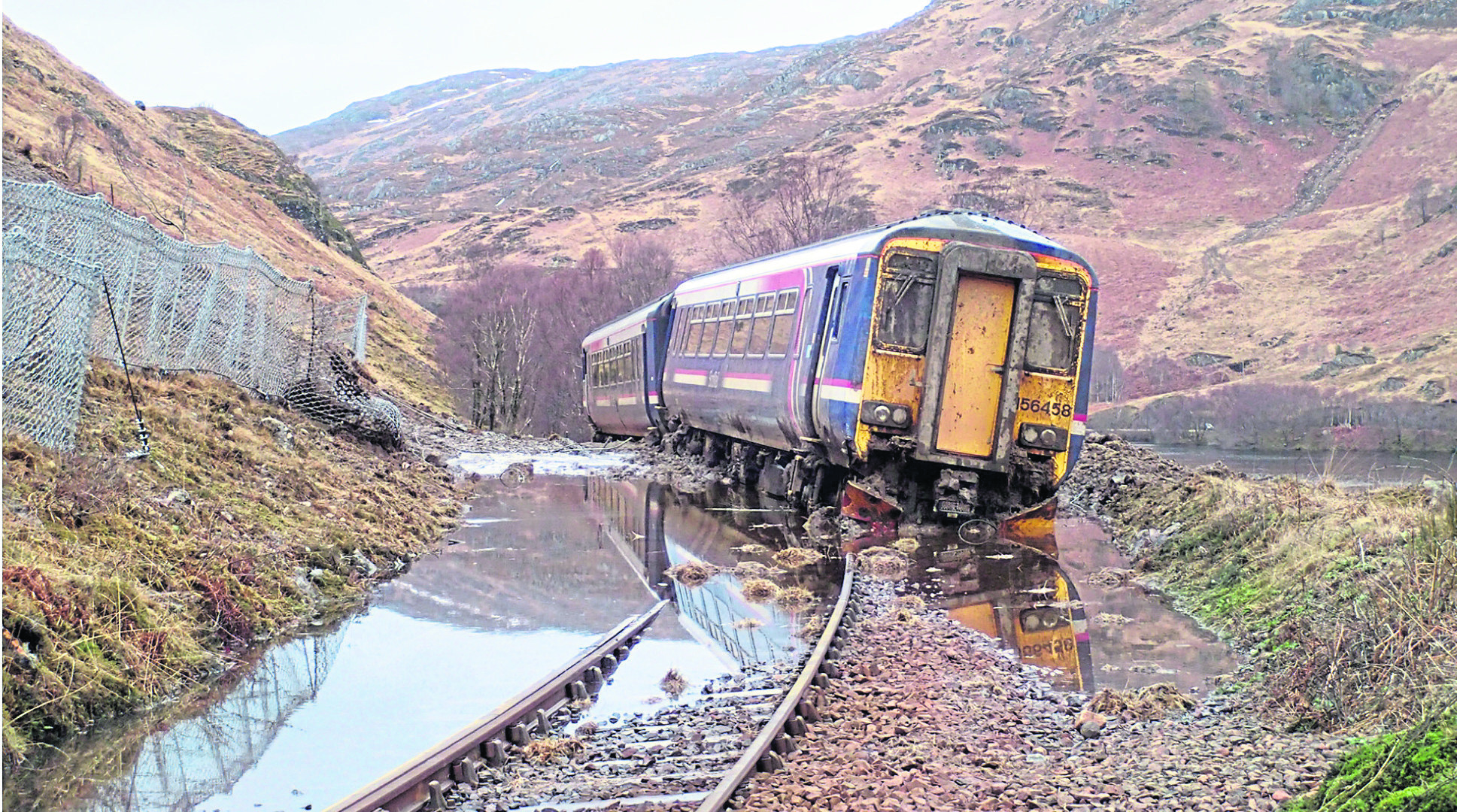 A derailed train with a landslip visable in the background at the side of Loch Eilt.

Picture from the rail accident report.