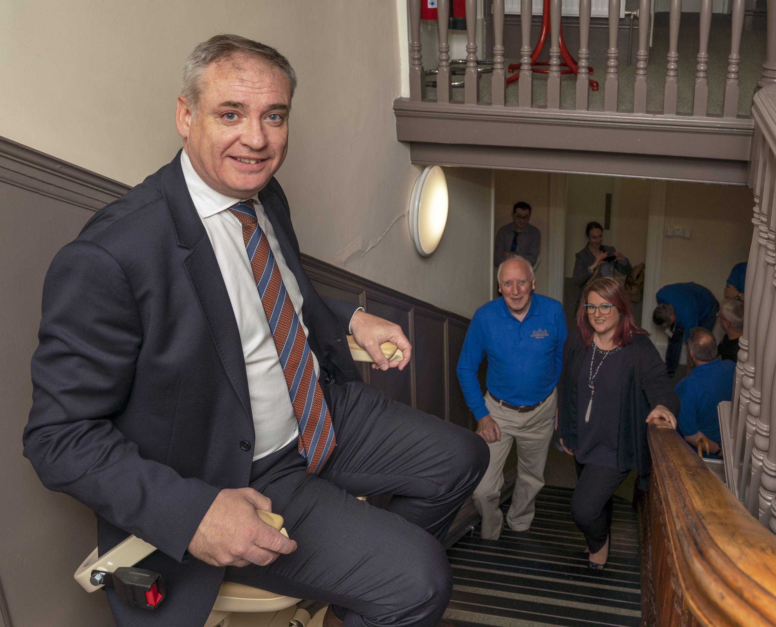 MSP Richard Lochhead uses the seat lift to negotiate the stairs watched by David Thow, Chairman of Fochabers Mens Shed and Morven Smith, Head of Community Investment SSE Plc.