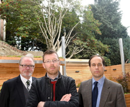 Sam Andrew (centre) of Ashley Road, in his back garden, with councillors John Cooke (left) and Martin Greig, showing the height of the overgrown trees of his neighbour which block out light to his garden and the rear of his house.