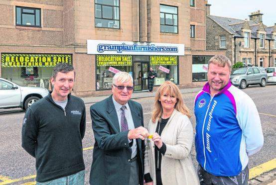 Royce Clark and his father James Clark, of Grampian Furnishers, hand over the keys to Jill and Jason Fletcher.