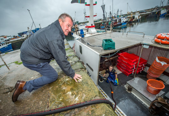 Hamish McPherson and a fisherman fuelling a boat.