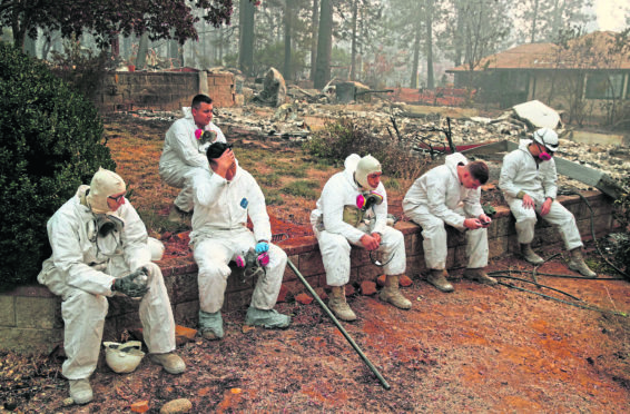 Members of the California Army National Guard take a break as they search burned homes for human remains in Paradise, California.