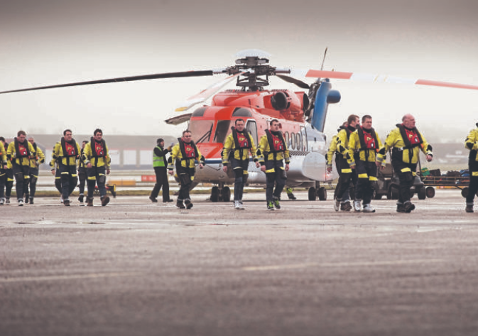 Offshore workers with a CHC Scotia helicopter at Aberdeen heliport.