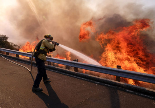 A firefighter battles a fire along the Ronald Reagan (118) Freeway in Simi Valley, California.