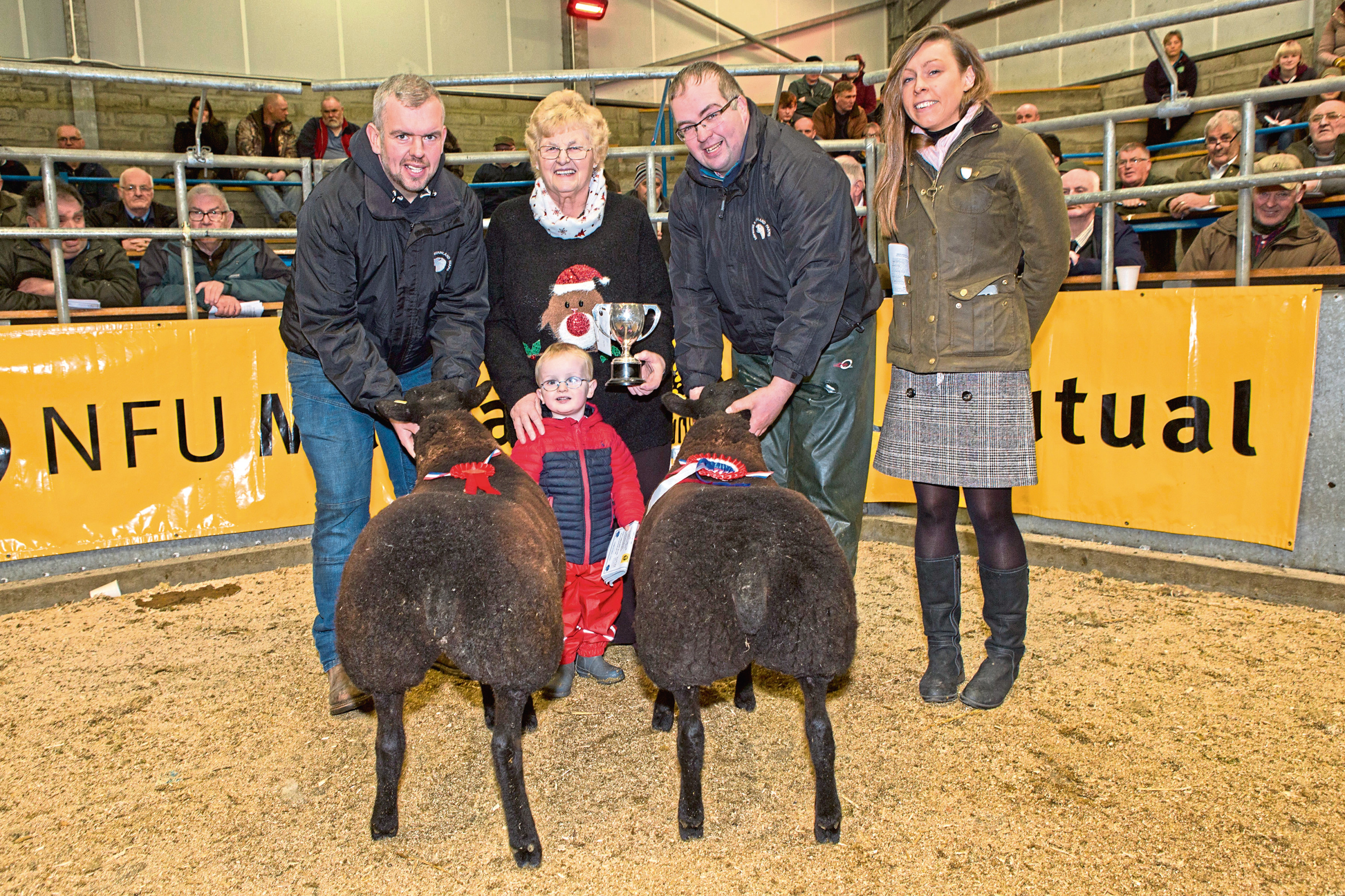 Kenneth Sutherland, (left), his two year old son Jack and Stephen Sutherland receiving the trophy from Joanna Mackay, who sponsored the competition. Looking on is buyer Jennifer Lamont.