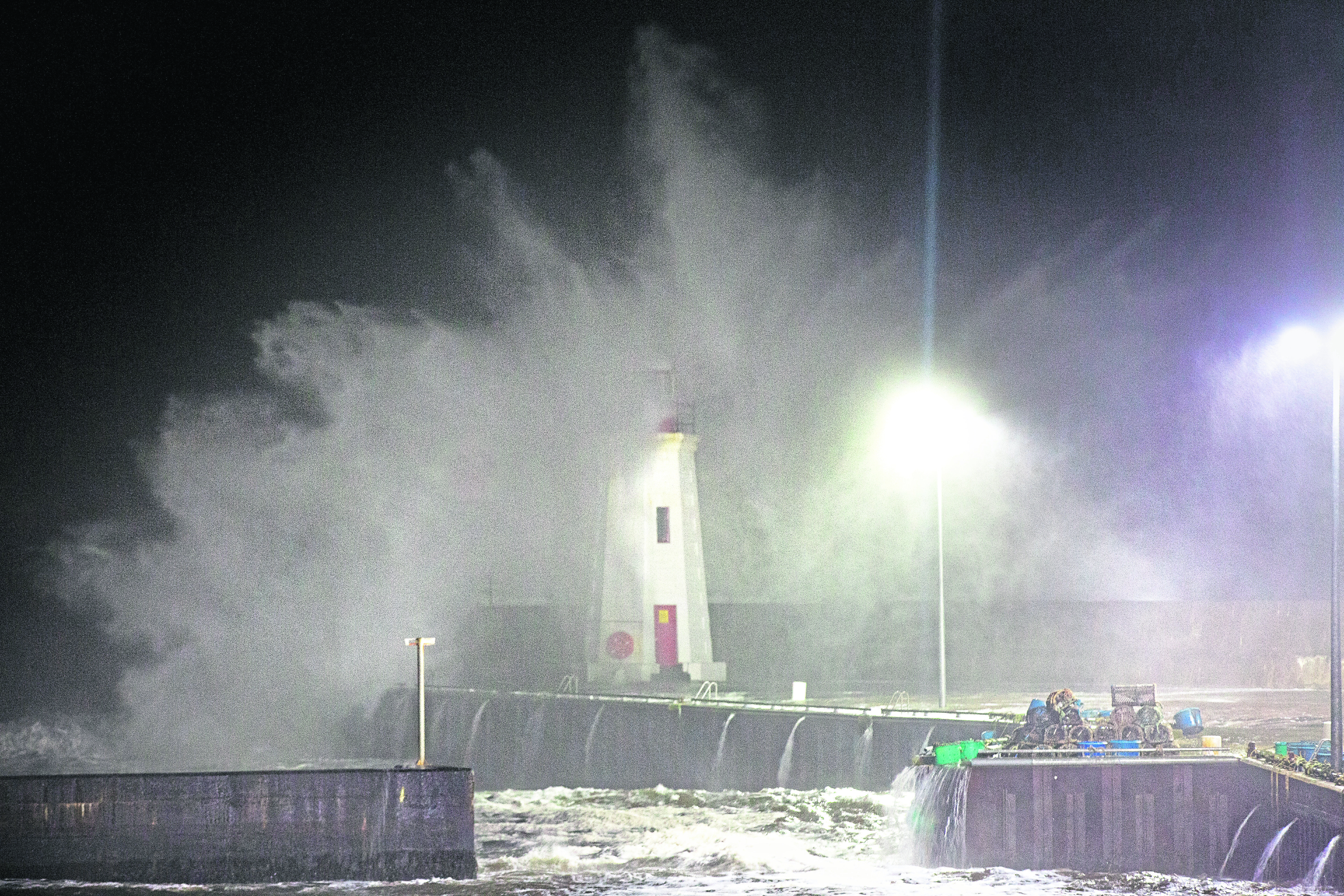 Waves crash over the lighthouse at Lybster Harbour, Caithness.