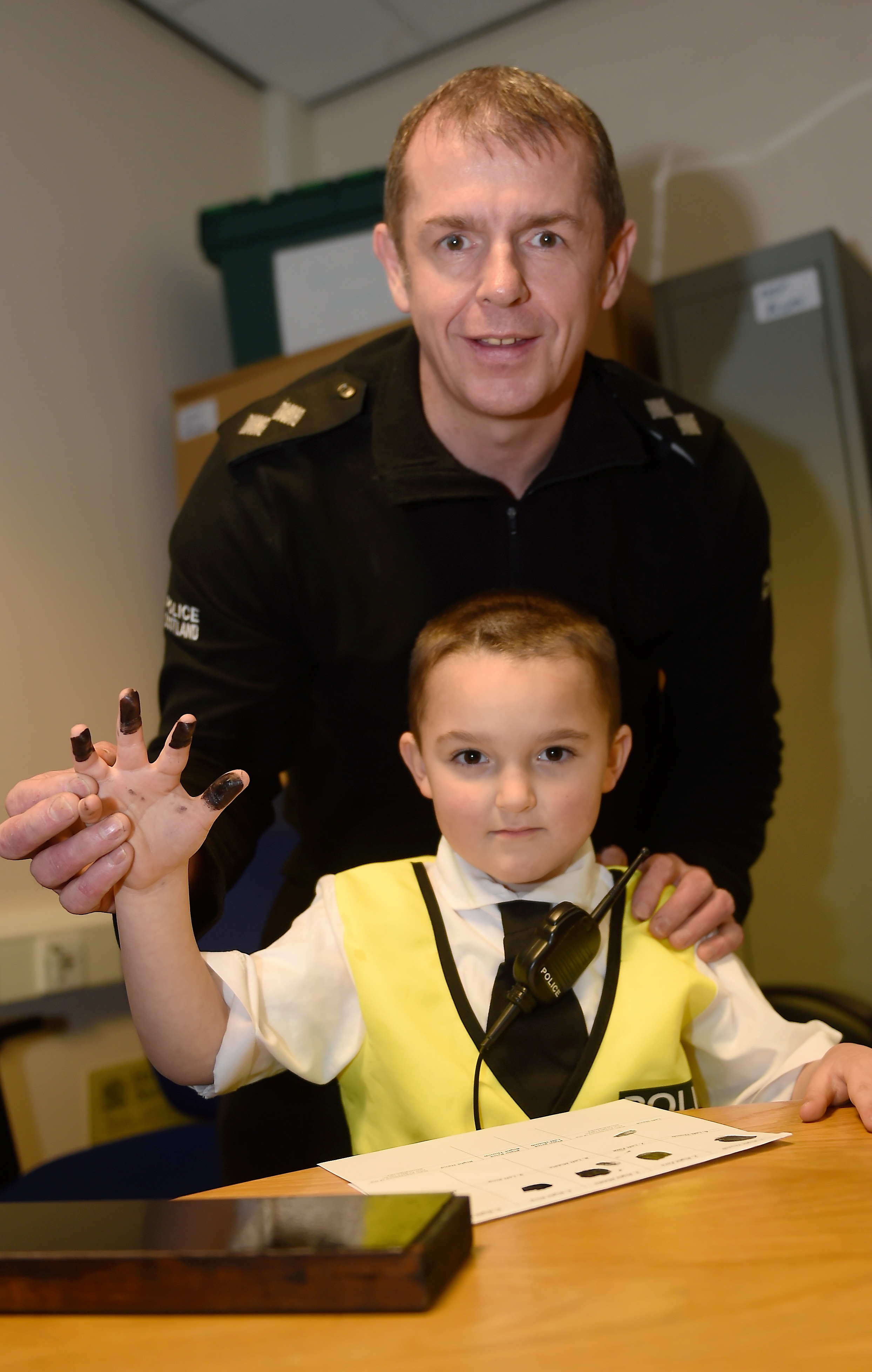 Picture by SANDY McCOOK 
Reporting for duty.........Brax Walker (5) of Garmouth at Elgin Police Station on Saturday afternoon.   Also in the photograph is Inspector Neil Campbell of Police Scotland.