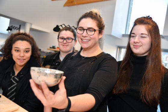 Technician Megan Falconer showing Banff pupils (L ro R) Ayesha Argo, Claire Campbell and Alana Cameron a hammered silver bowl at the Smiddy