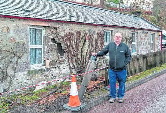 Kevin at the damaged part of his home and demolished lampost.