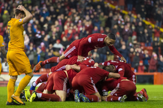 Aberdeen players mob Lewis Ferguson after his late winner.