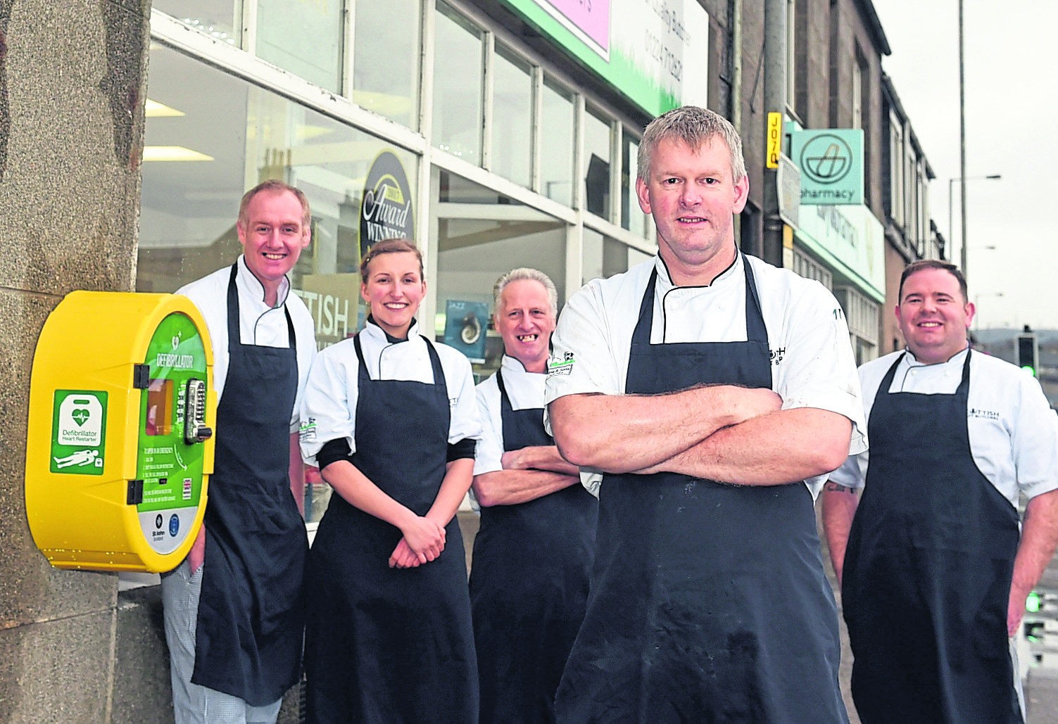 Kenny Milne, front, with his team from H&S Milne and the wall-mounted defibrillator.