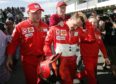 Michael Schumacher walks with Ferrari teammates in the pits