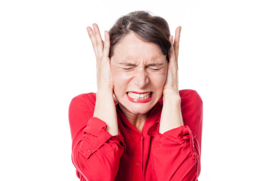 A woman covering her ears because of a loud noise.