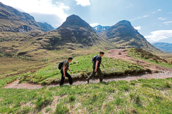 Walkers near the Three Sisters mountain range in the Highlands.