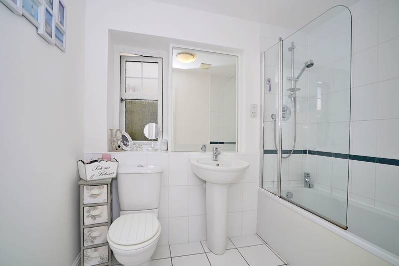 Bathroom: Fitted with a white three-piece suite, complete with an overbath mixer shower and shower screen