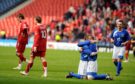 Aberdeen player Darren Mackie walks to the dugout as the Queen of the South players celebrate.