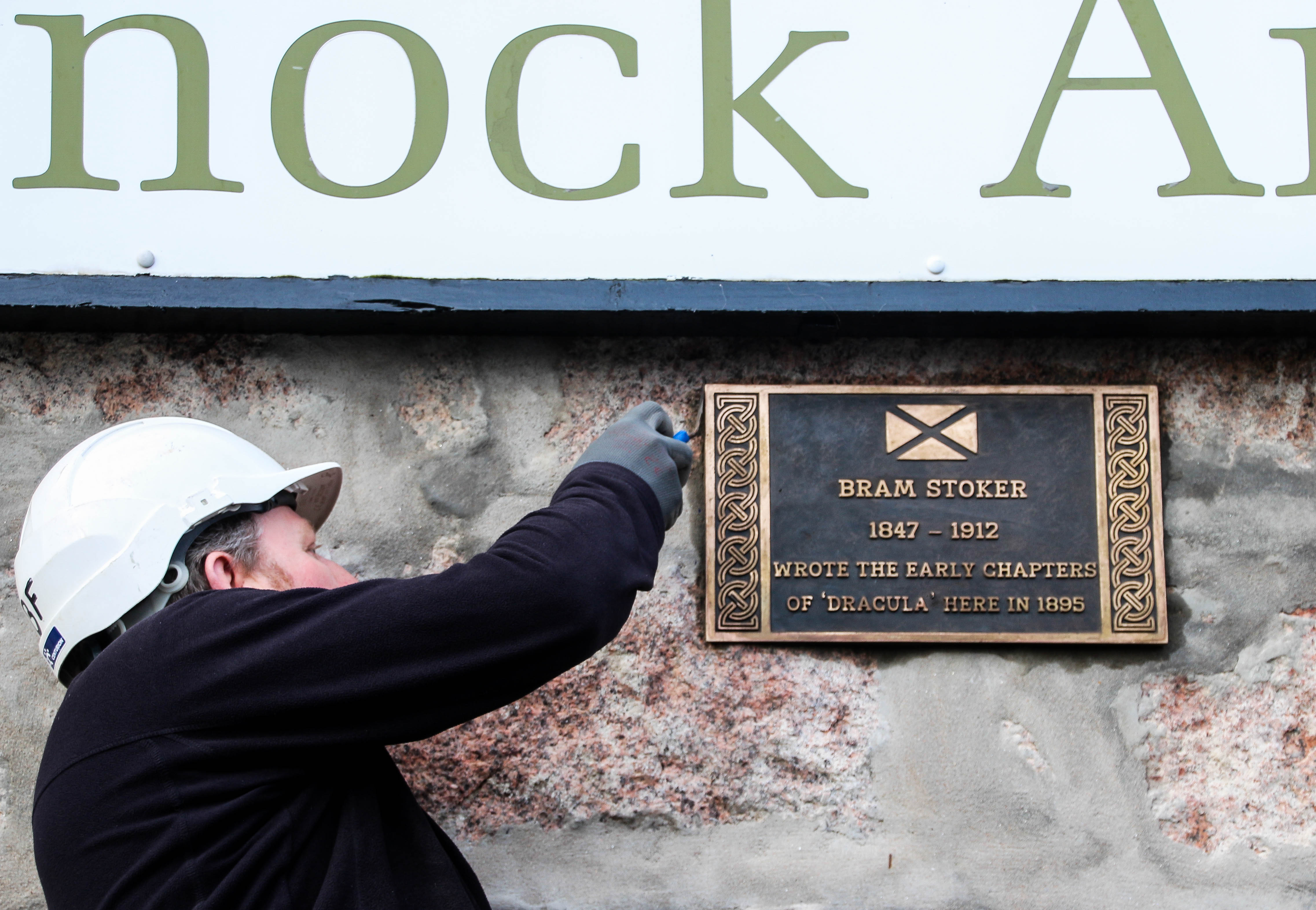 A workmen installs the plaque at the Kilmarnock Arms Hotel