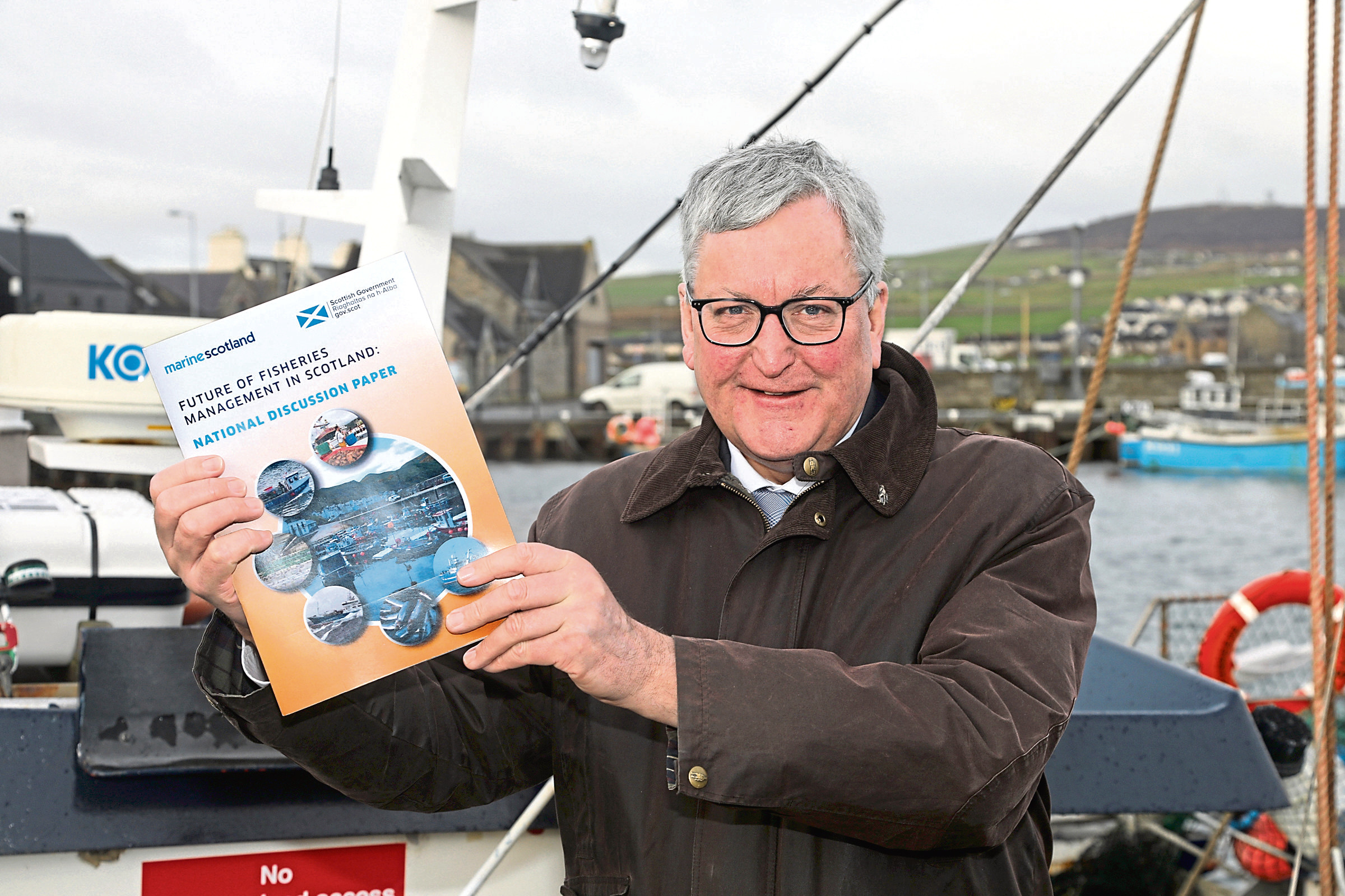 Ken Amer - Fergus Ewing brandishing the Future of Fisheries Management in Scotland paper at Kirkwall Harbour, Orkney