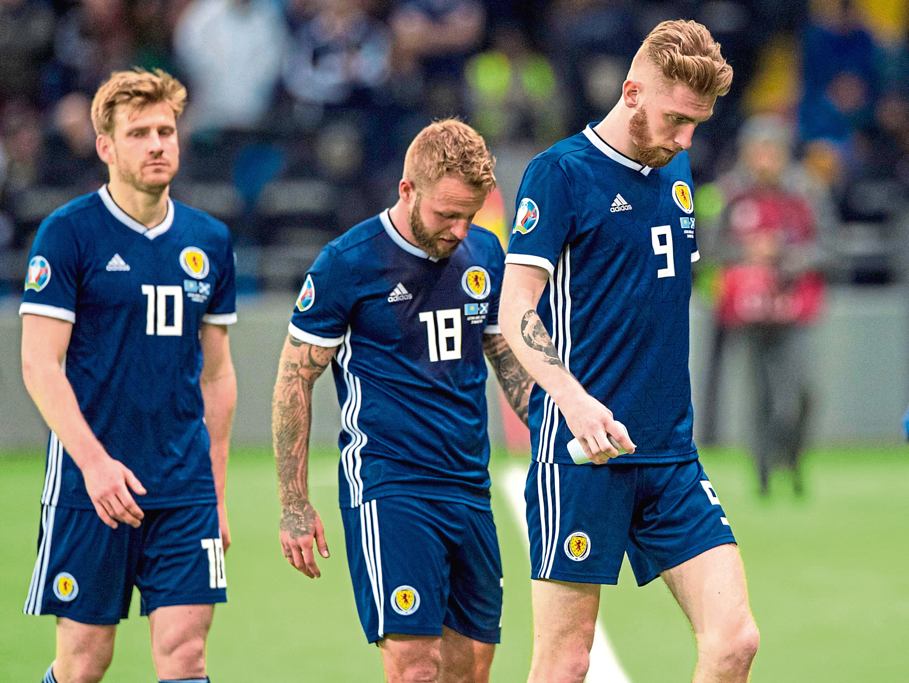 (Left-Right) Scotland's Stuart Armstrong, Johnny Russell and Oli McBurnie trudge off the field at full-time.