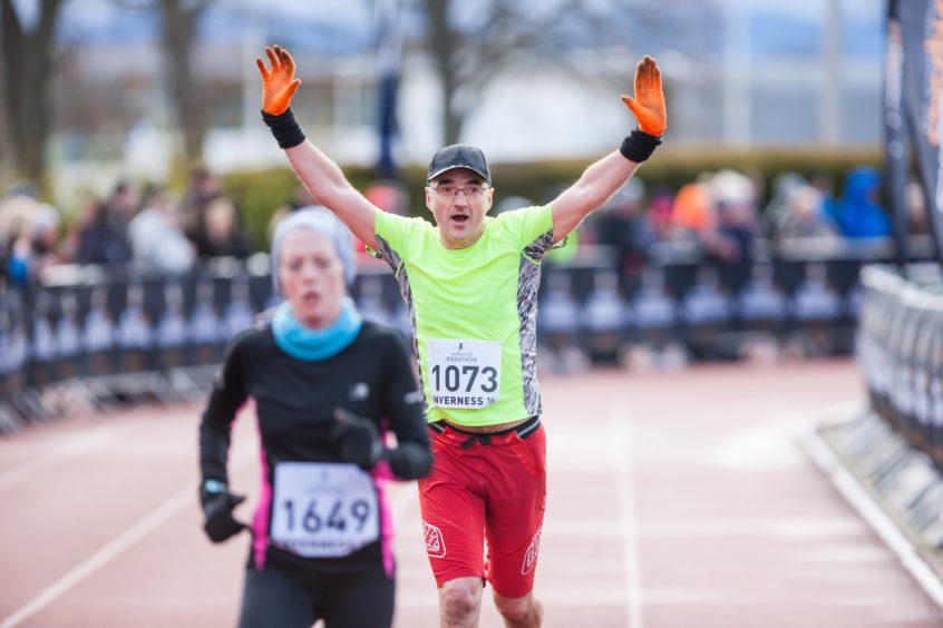 A runner celebrates as he crosses the line at the Inverness 1/2 Marathon.