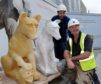 Ivan Navaro and Derek Cunningham, both sculptors and conservators with a model and carved wolf.