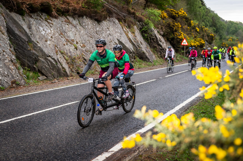 A pair of Macmillan Cancer Support cyclists riding a tandem bike as part of the Etape Loch Ness.