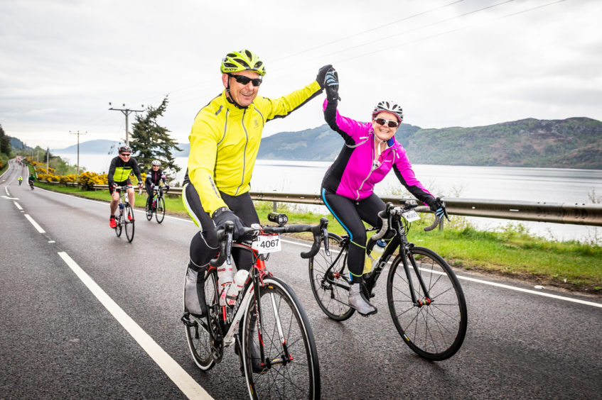 Cyclists making their way along the A82 with Loch Ness in the background.