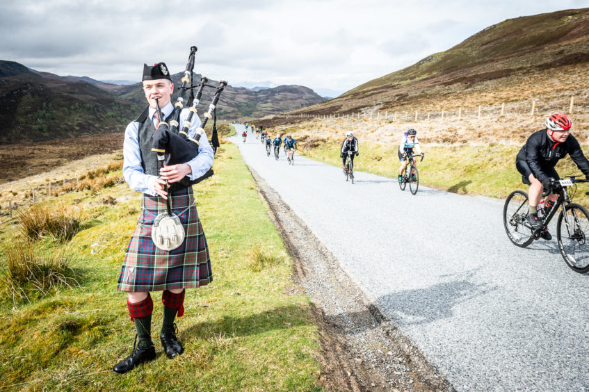 A lone piper waits to pipe the riders home at the top of the Suidhe viewpoint and the end of the King of the Mountain stage.