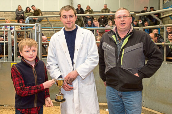 James Gunn, centre, was presented his trophy on behalf of sponsors, Mackay, West Greenland, by 7-year-old Dhail Mackay, whose father, Andrew, looks on.