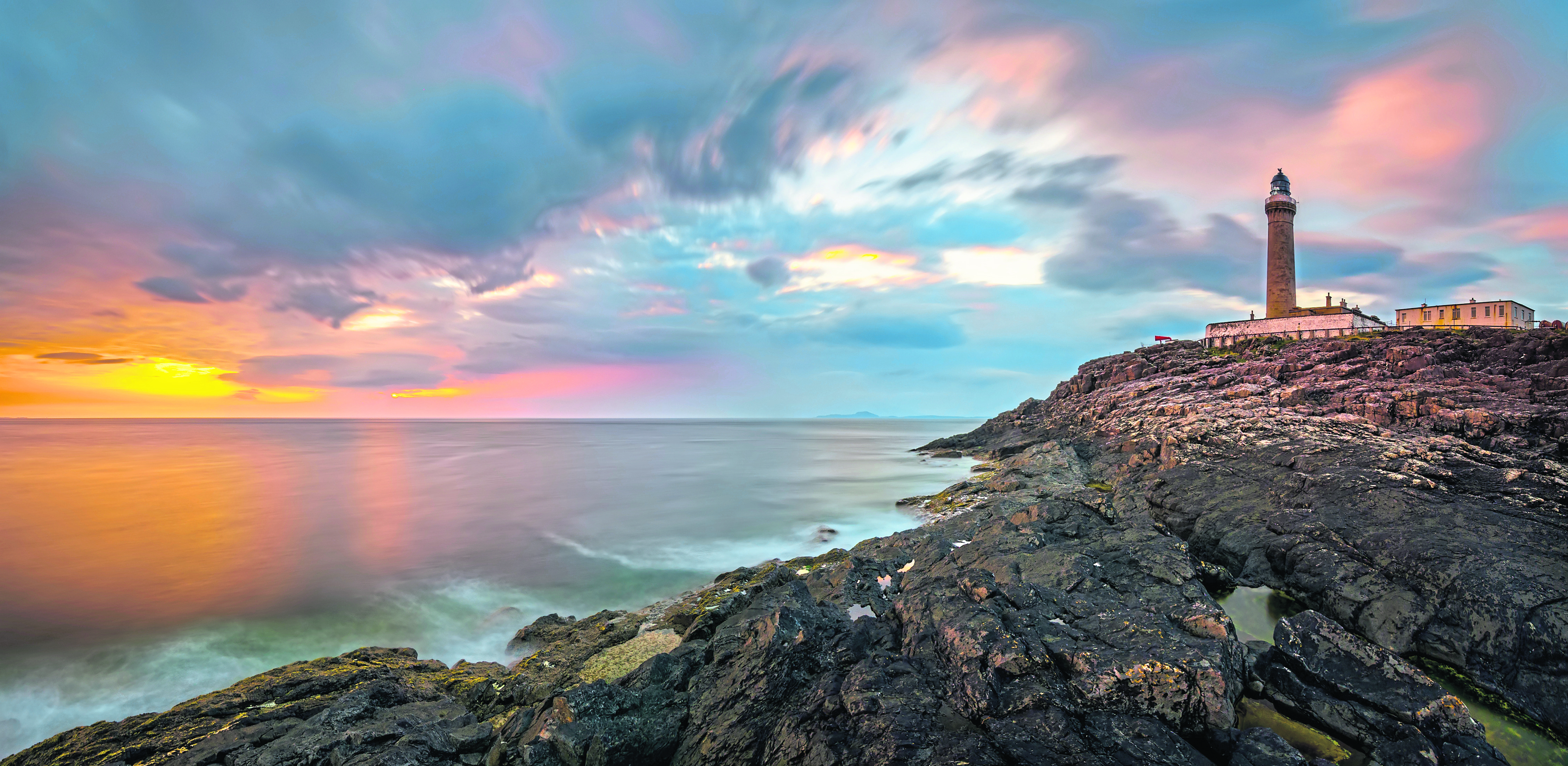 Lighthouse on cliffs of Ardnamurchan Point in colorful sunset,