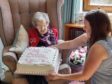 Kate Ingram being presented with her birthday cake by one of her great-nieces Rhona Bowie