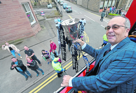 Chairman Roy MacGregor savours the moment with the trophy on the top deck of the bus.