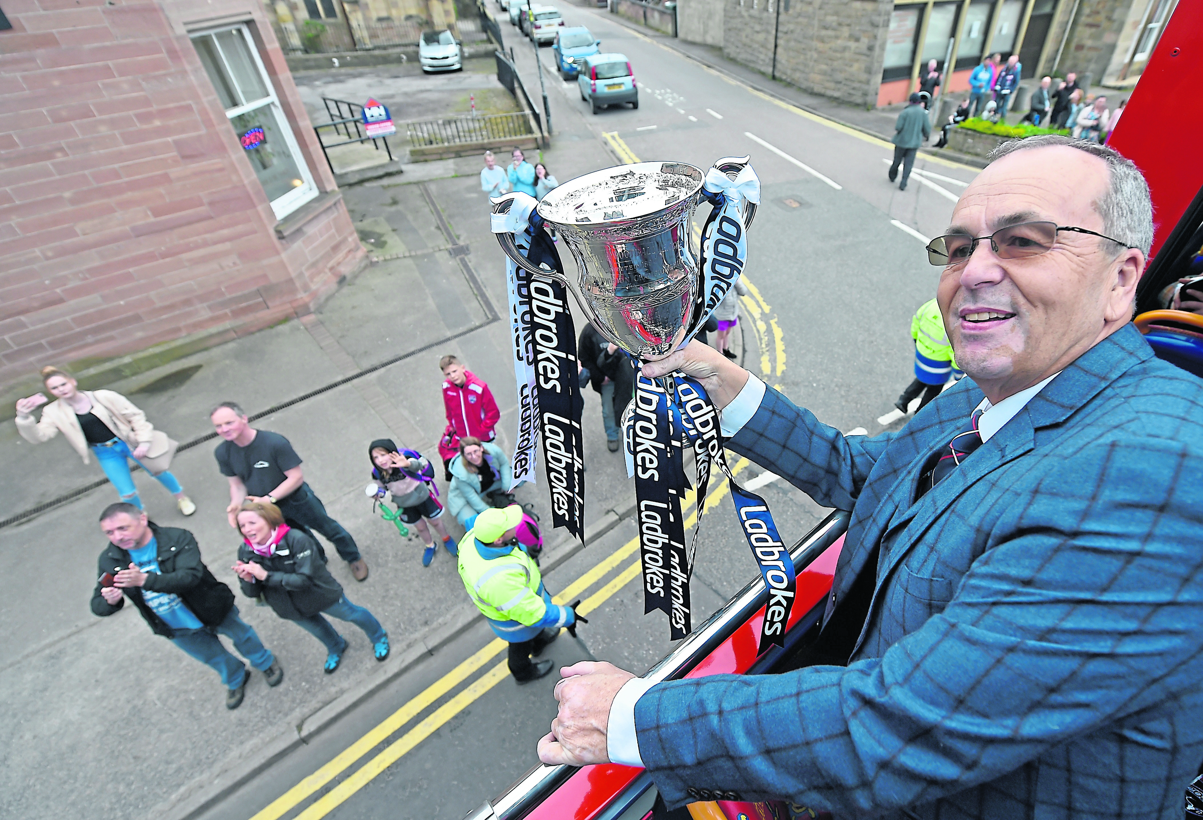 Chairman Roy MacGregor savours the moment with the trophy on the top deck of the bus.