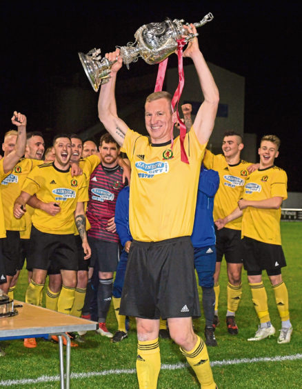 Evening Express Aberdeenshire Cup. Harlaw Park. Banks o'Dee (blue) v Cove. Eric Watson lifts the cup.