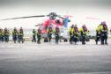 Offshore workers with a CHC helicopter at Aberdeen heliport.