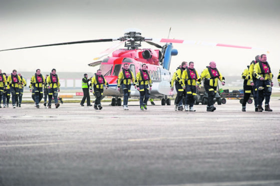 Offshore workers with a CHC helicopter at Aberdeen heliport.