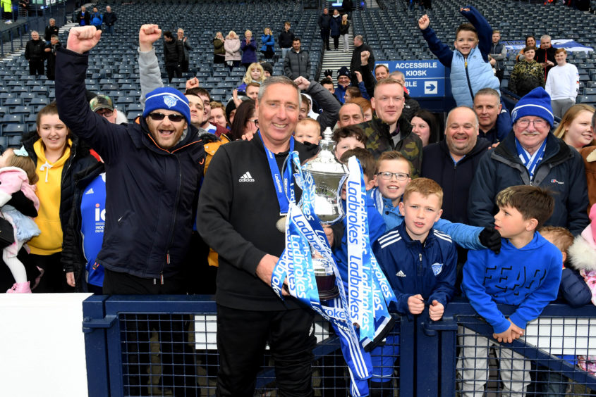 Peterhead manager Jim McInally celebrates with the Ladbrokes League 2 trophy and fans in 2019.