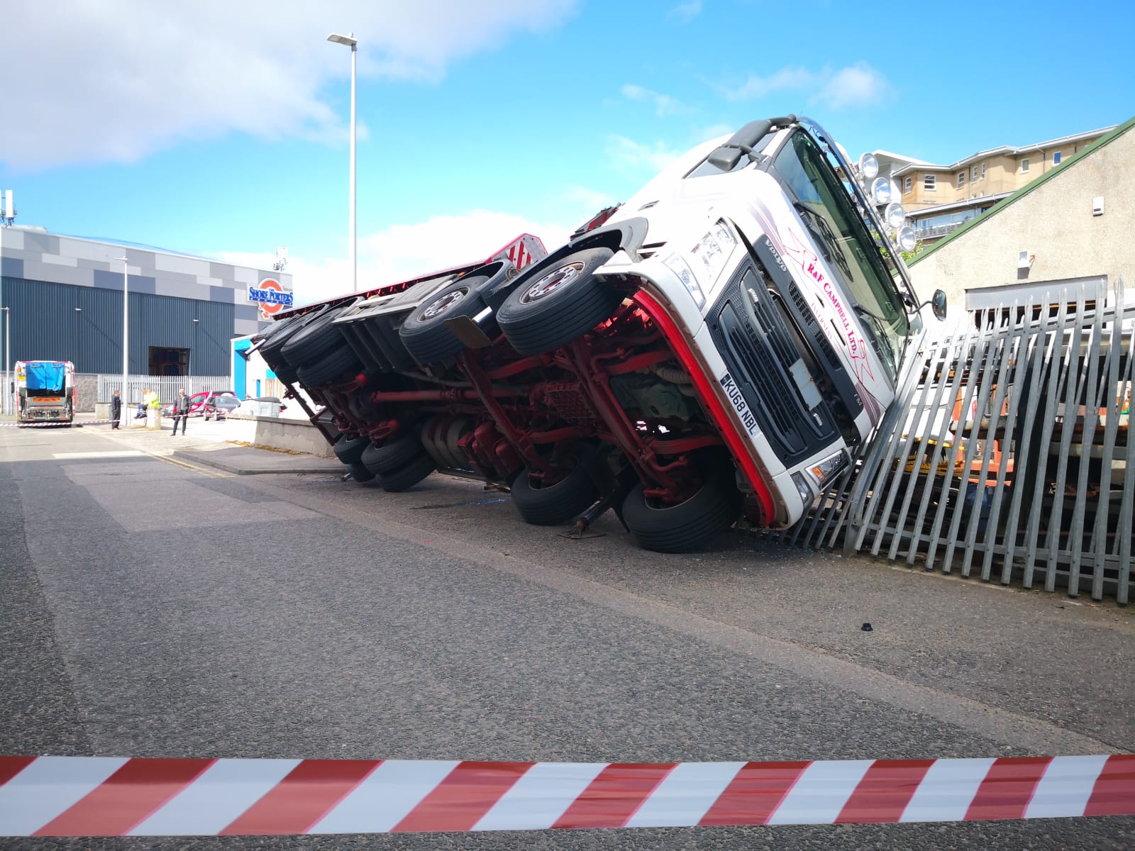 A lorry toppled over during a delivery and pinned a man to a fence.