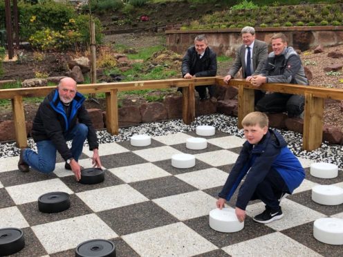 Committee member Ian Garden and grandson Callum playing the first game on the board watched by, left to right, Robert Stephen of Celebrations of Turriff, councillor Iain Taylor and Friends of Turriff Cemetery founder Fraser Watson