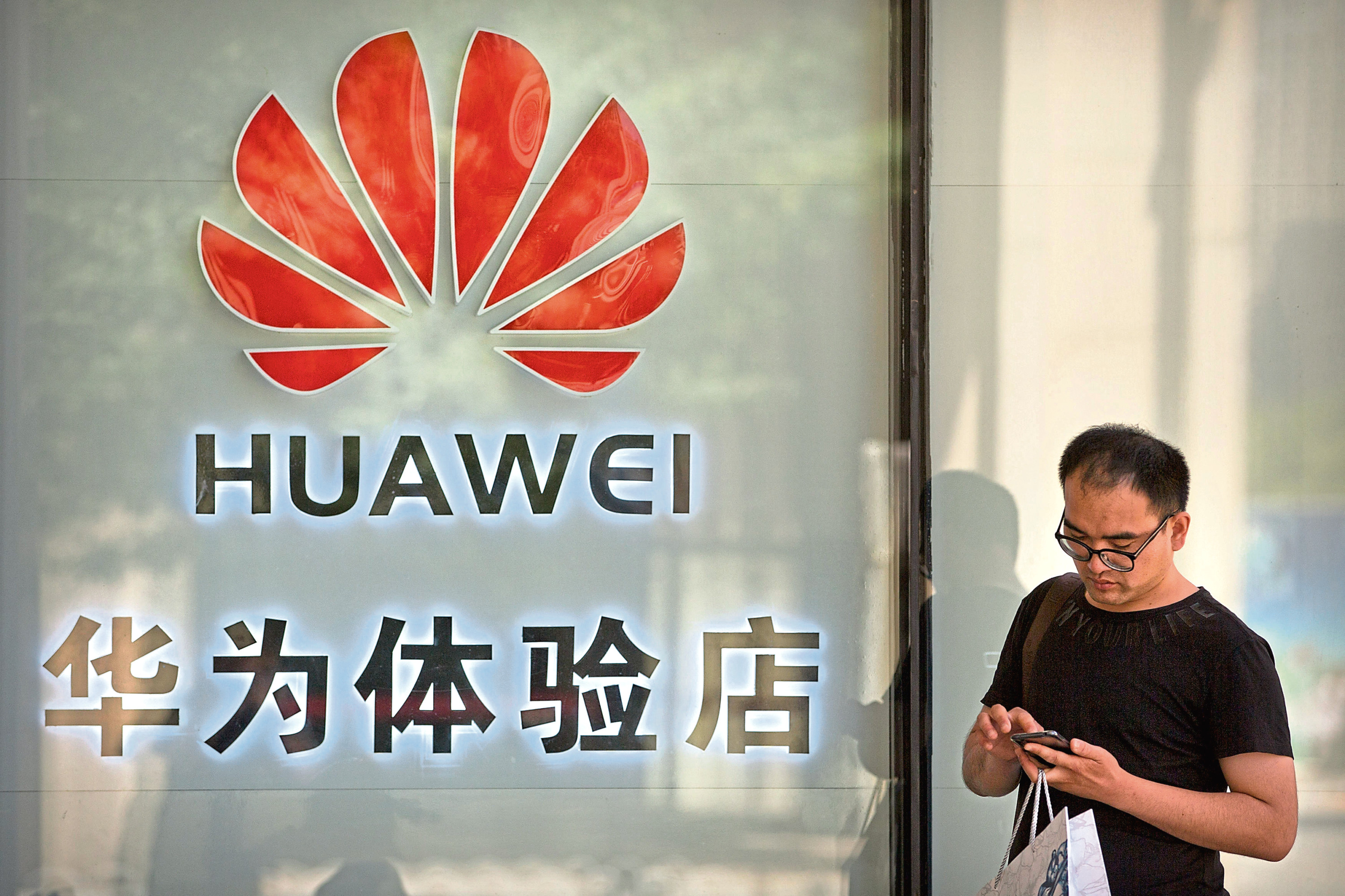 A man uses his smartphone outside of a shop selling Huawei products at a shopping mall in Beijing, Wednesday, May 29, 2019. Chinese tech giant Huawei filed a motion in U.S. court Wednesday challenging the constitutionality of a law that limits its sales of telecom equipment, the latest action in an ongoing clash with the U.S. government. (AP Photo/Mark Schiefelbein)