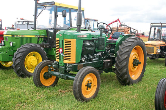 A 1950s Turner Yeoman of England, bearing the distinctive green and yellow colour scheme, stands next to a more modern John Deere model