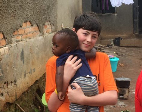 Ellon Academy pupil Bobby Boardman, 14, with a Ugandan child.