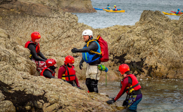 Chris McCann leading a coasteering group on behalf of Outfit Moray